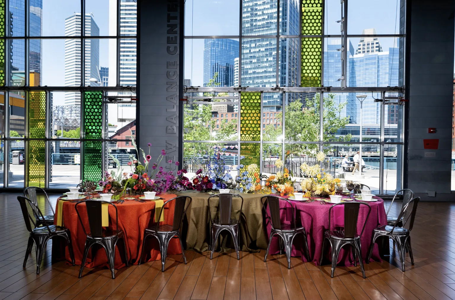 Round tables set with colourful linens and floral centrepieces for an event at the New Balance Center in Boston, catered by MAX Ultimate Food