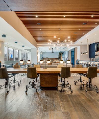Long communal table set with task lamps under the wood-slat ceiling at Echelon Innovation Center